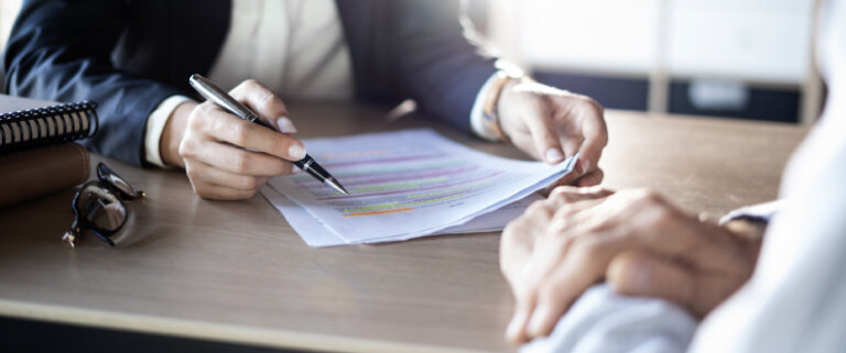 Close-up of a professional reviewing and highlighting a document during a discussion.