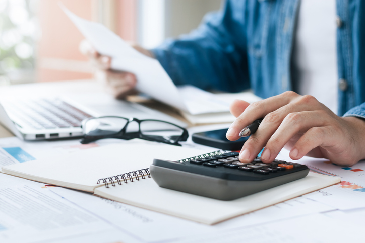 client doing taxes and looking at disability forms with calculator and glasses near a computer in florida