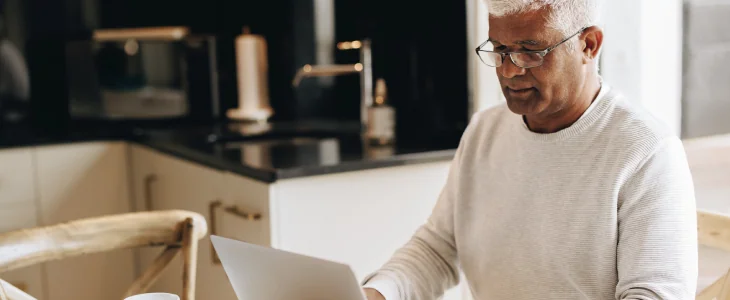 an elderly man sitting looking at his laptop ssdi