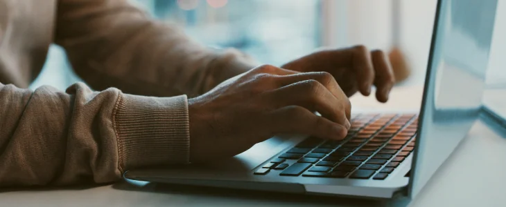 a person typing on their laptop on a table ssdi